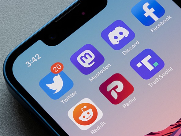 Social network icons on phone screen, including Reddit, Twitter and Mastodon